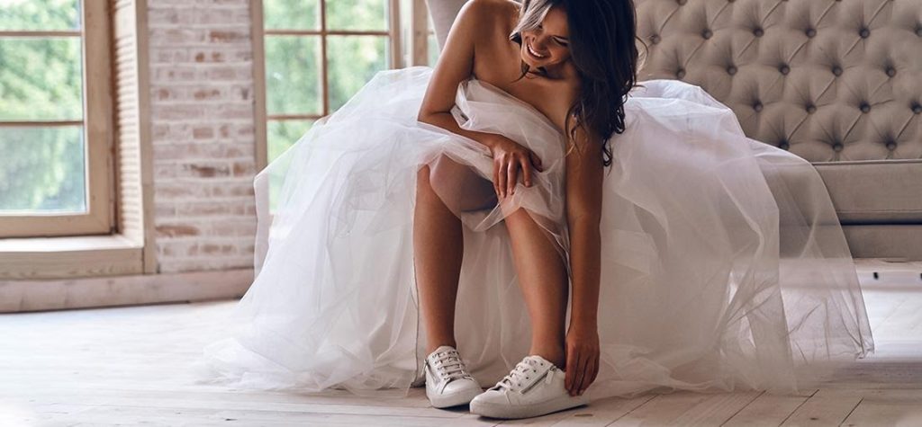 Νύφη που φοράει λευκά sneakers με νυφικό