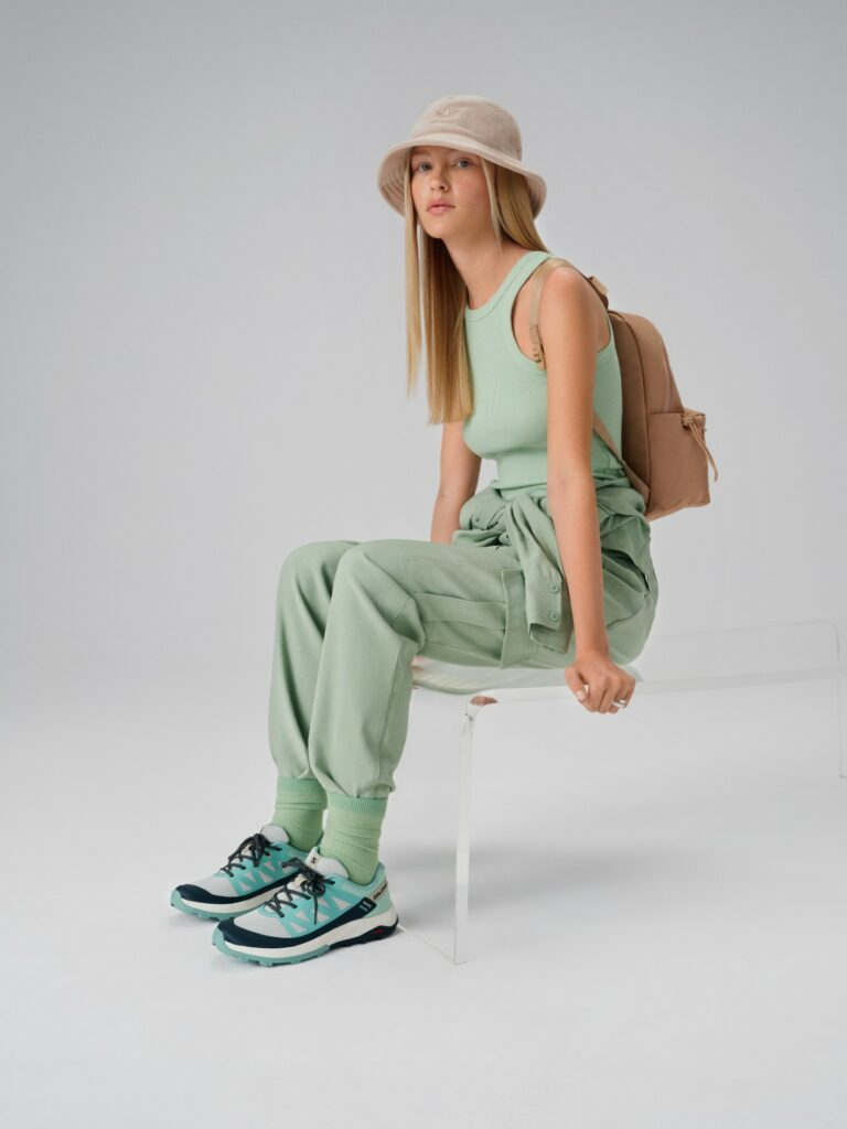 Μοντέλο ντυμένο με streetwear style με μπεζ καπέλο adidas και παπούτσια Salomon
